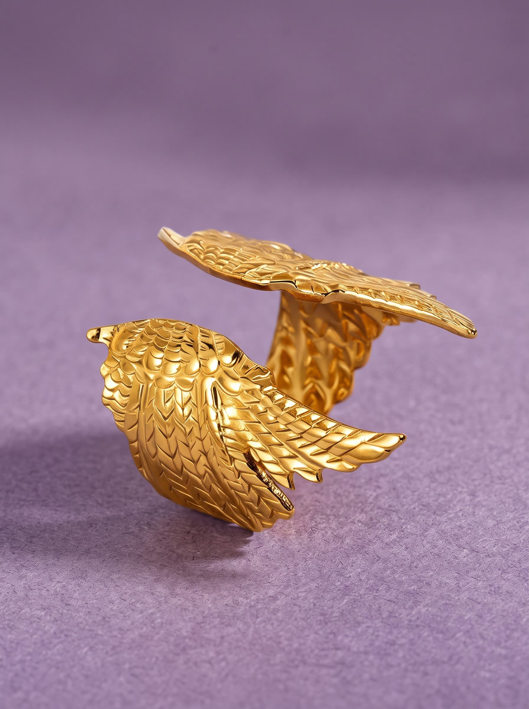 Gold angel wings statement ring on purple fabric
