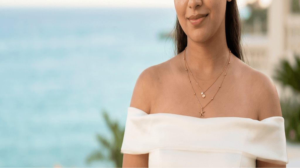 Model wearing a gold starfish necklace by the sea