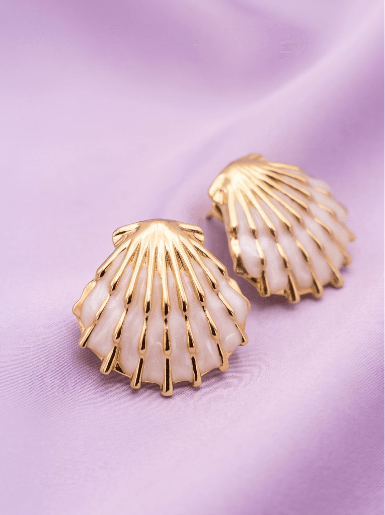 Gold scallop shell earrings on lilac fabric