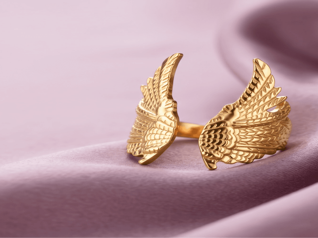 Gold angel wings ring on pink satin